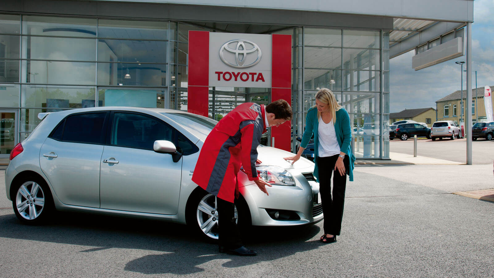 Toyota servicetekniker hjälper kund med att kolla på bilen utomhus