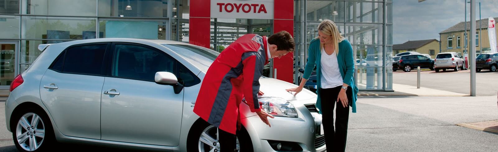 Kund och tekniker kollar på bil under Toyotaservice