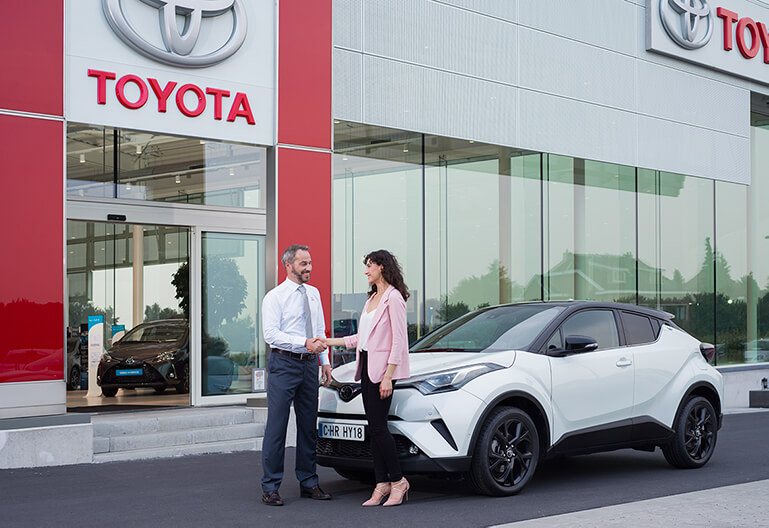 Kvinna skakar hand med Toyota återförsäljare efter ett lyckat köp