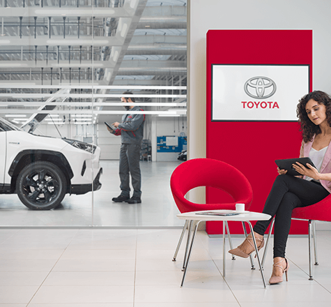 En kvinna som väntar medan hennes bil får service enligt bilgaranti hos Toyota