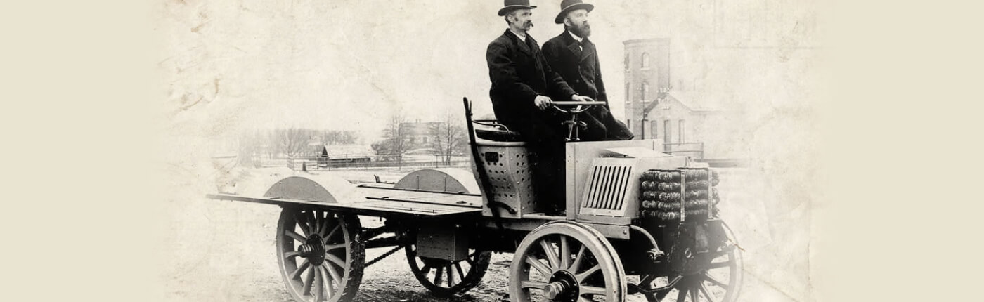 En svartvit bild på en gammal bil som två män kör.