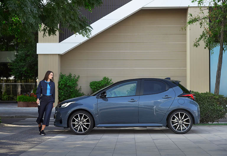 En kvinna och en blå Toyota Yaris.