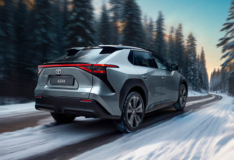 En Toyota bZ4X kör i ett vinterlandskap.