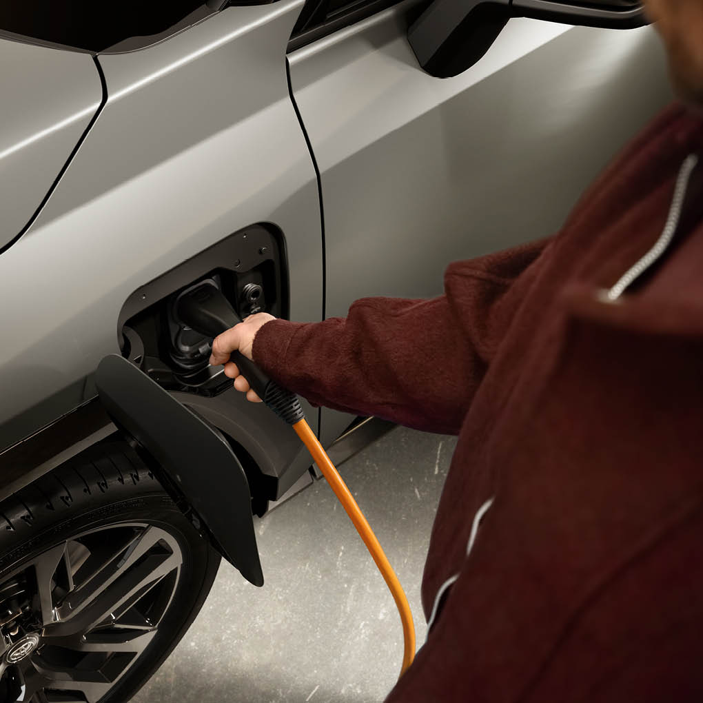 En hand sätter in en laddare i en bil.