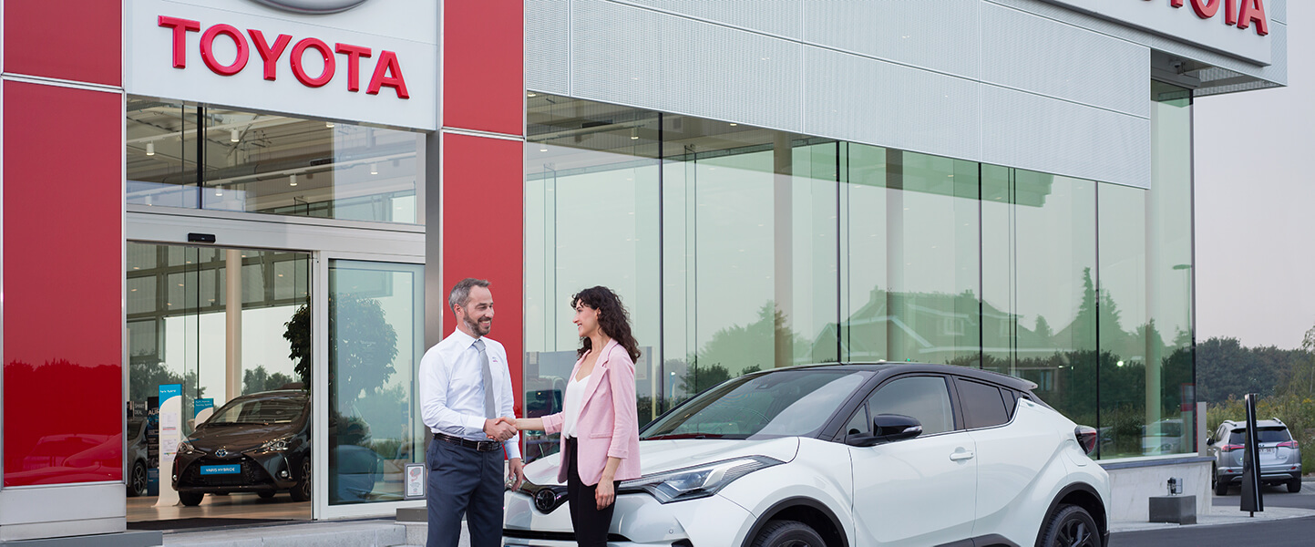Kvinna skakar hand med Toyota återförsäljare efter ett lyckat köp